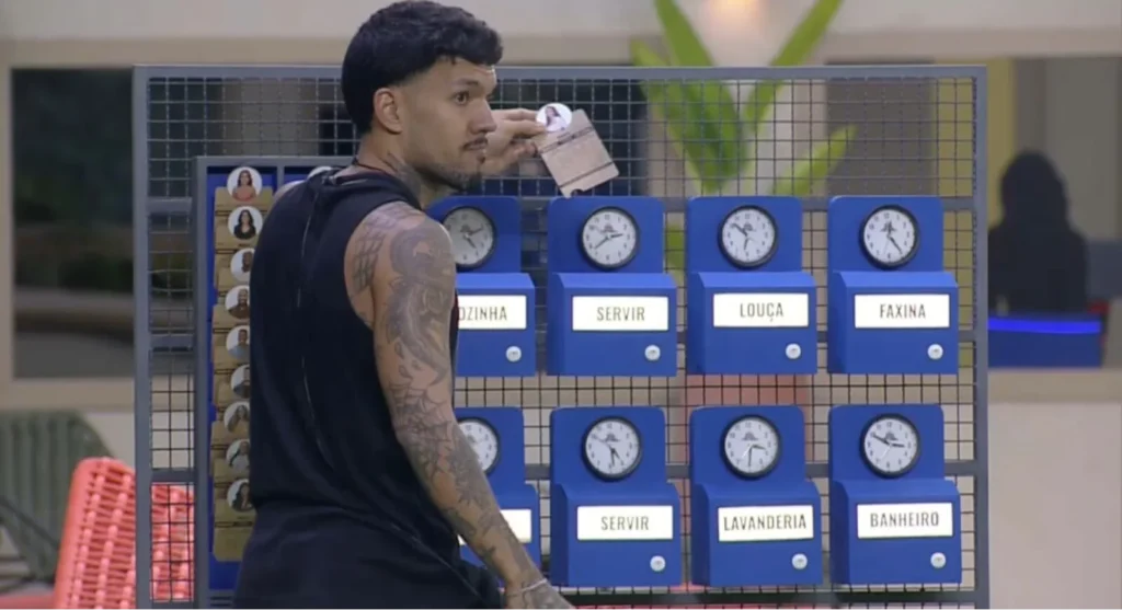 Luis Fellipe na Casa do Patrão, em frente à parede de tarefas das três casas