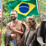 Rene Murad e Marina Fukushima em frente a bandeira do Brasil em Largados e Pelados Campeoes do Mundo